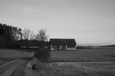 Built structure on field by road against sky