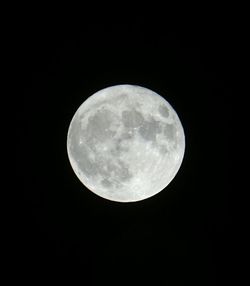 Low angle view of full moon against black sky
