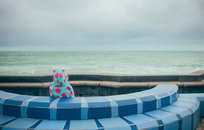 Little girl in a bathrobe sitting facing the sea