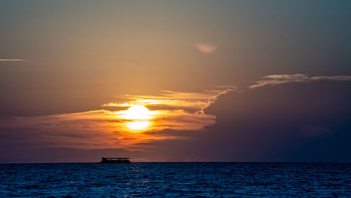 Scenic view of tour boat on sea against sky during sunset in silhouette 