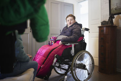 Disabled teenage girl sitting on wheelchair at home