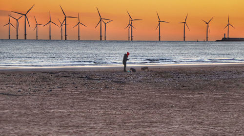 Woman on beach against sky during sunset