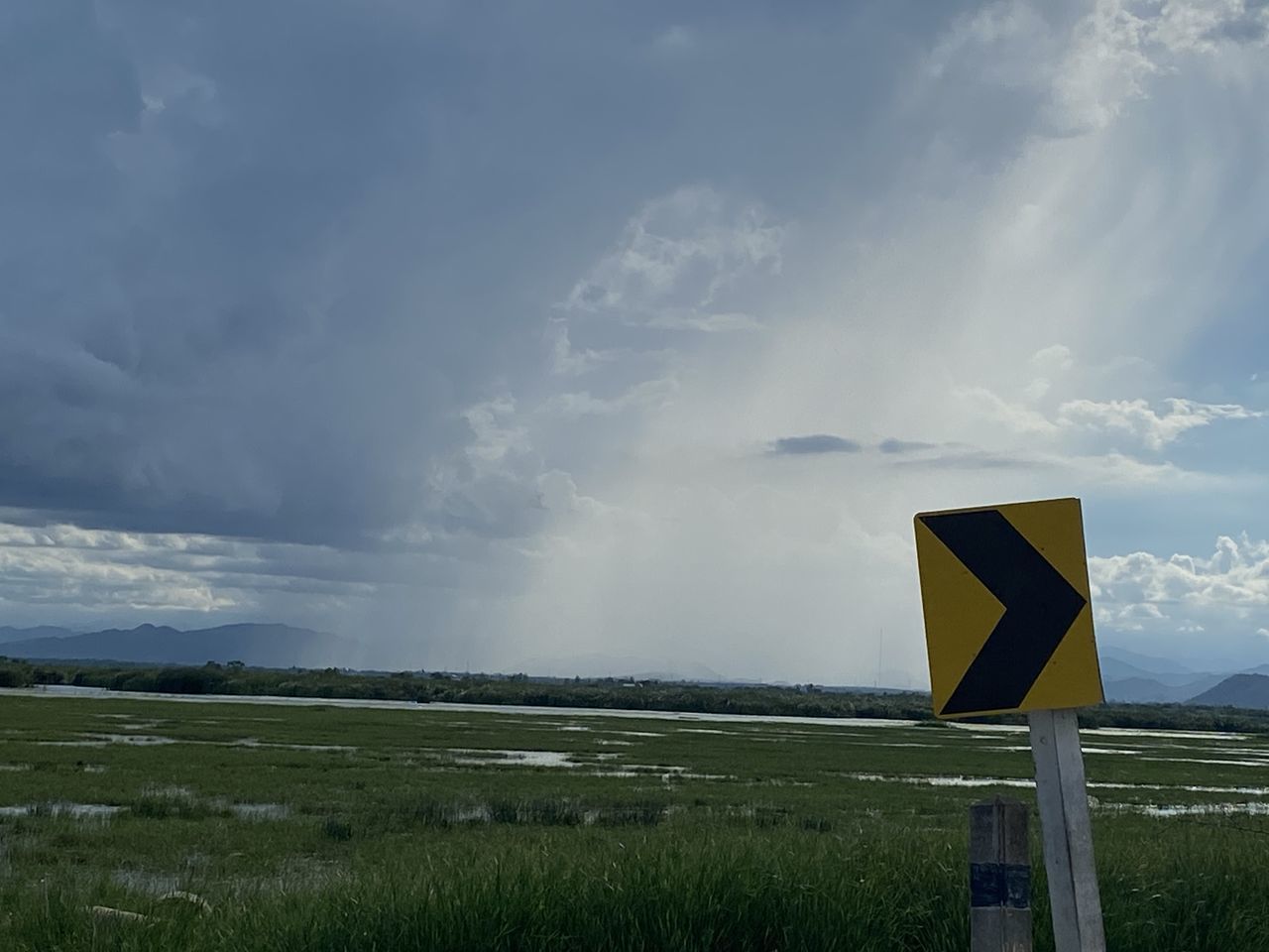 ROAD SIGN ON FIELD AGAINST CLOUDY SKY