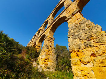 Low angle view of old ruins against blue sky