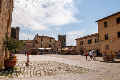 People walking on street amidst buildings in city