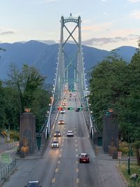 Vehicles on road by suspension bridge in city