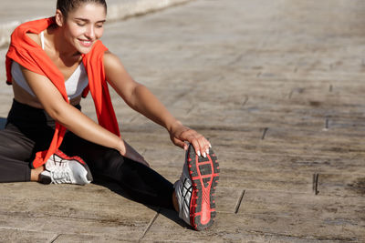 Woman stretching while sitting outdoors