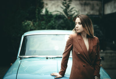 Woman looking away while standing by car