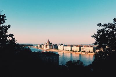 River by cityscape against clear sky