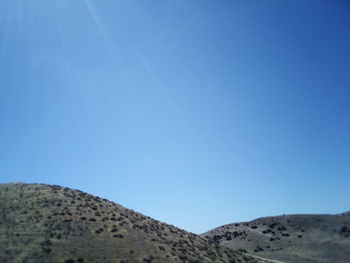 Scenic view of arid landscape against clear blue sky