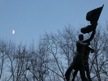 Low angle view of silhouette statue against clear blue sky