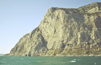 Rock formations by sea against clear sky