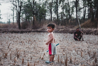 Boy standing on field against trees