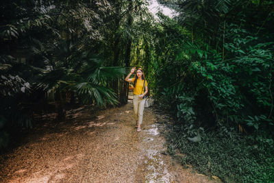 Woman walking amidst plants in forest