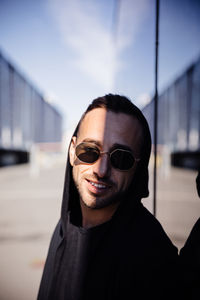 Man wearing sunglasses while leaning against glass wall