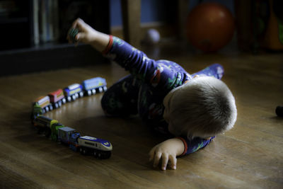 Boy playing with toy train on floor at home