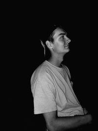 Young man looking away against black background