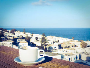Coffee cup by sea against sky
