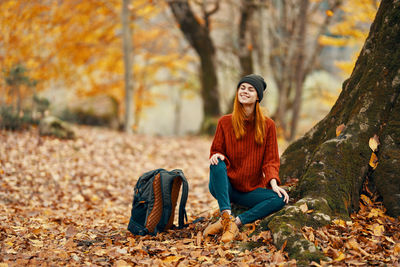 Portrait of smiling young woman sitting on land during autumn