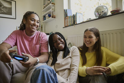 Happy girl enjoys playing video game with her friends at home