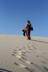 Low angle view of woman walking on sand dune at beach