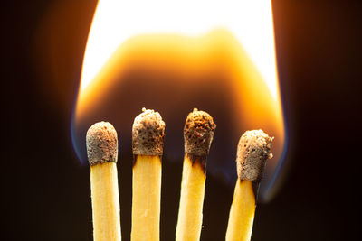Close-up of burning candles against black background