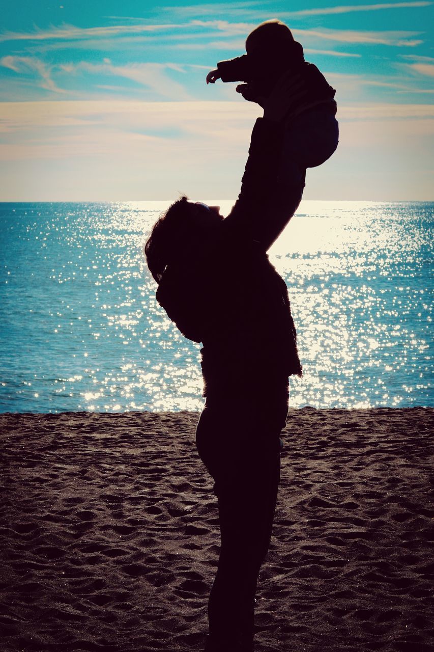 SILHOUETTE WOMAN STANDING ON BEACH AGAINST SEA DURING SUNSET