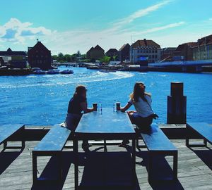 People sitting in water against clear sky