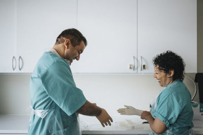 Happy male and female surgeons wearing gloves in hospital