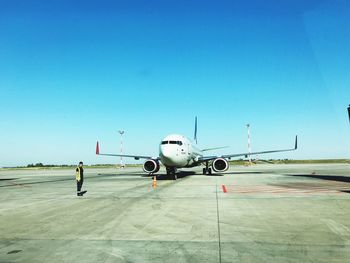 Airplane on airport runway against clear blue sky