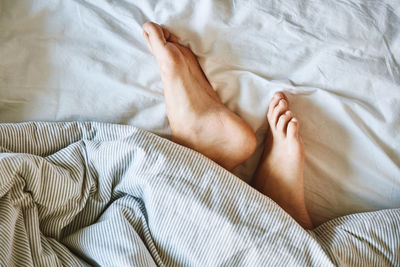 Morning concept, woman sleeping in bed, naked female legs under blanket