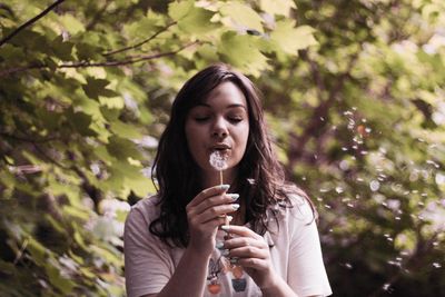 Close-young woman blowing dandelion 