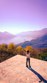 Rear view of man standing on mountain against sky