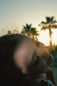 Close-up of smiling girl against sky during sunset