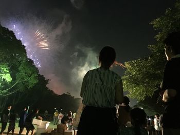 People looking at firework display during celebration at night