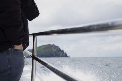 Rear view of man standing by sea against sky