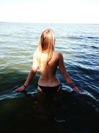 Rear view of shirtless boy in sea against sky