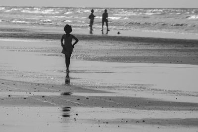 Girl walking on sand against sea at beach