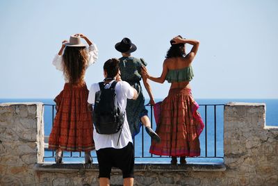 Rear view of people standing against clear sky