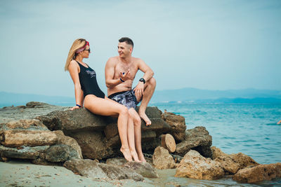 Young couple spending leisure time at beach against sky