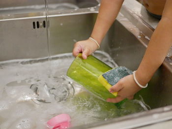 Midsection of person holding ice cream in kitchen