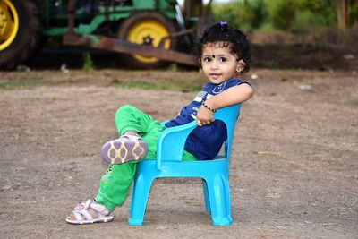 Side view of cute girl looking away while sitting on chair