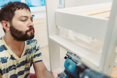 Side view of man looking through window