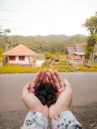 Midsection of woman holding hands in front of building
