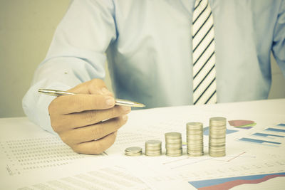 Midsection of businessman analyzing data on desk in office