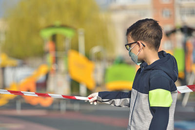 Close-up of boy wearing mask standing outdoors