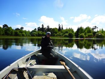 Mature woman sitting on boat sailing in lake against sky