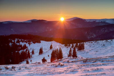 Scenic view of mountains against sky during winter at sunset