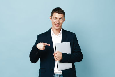 Portrait of young man standing against blue background