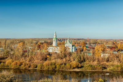 Scenic view of lake by buildings against clear blue sky